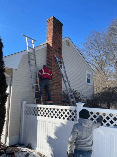 Chimney technicians working beside snowy home